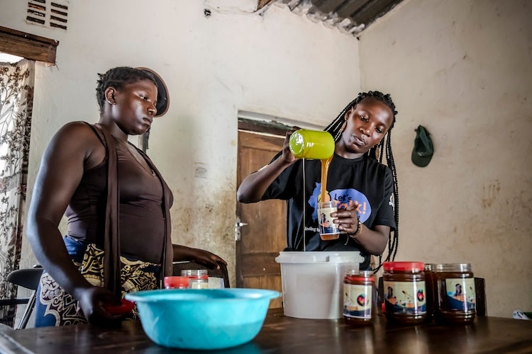 Two young women in Malawi filling jars.