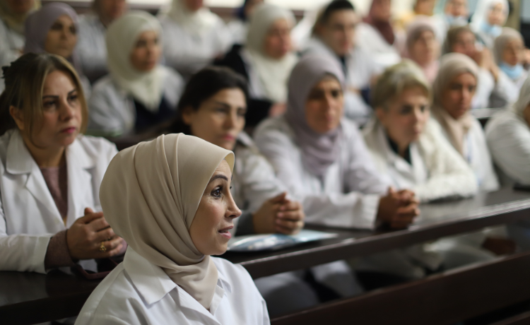  Au premier plan, une sage-femme portant une blouse blanche et un voile prend la parole, au second plan apparaissent de nombreuses sages-femmes en blouse blanche.
