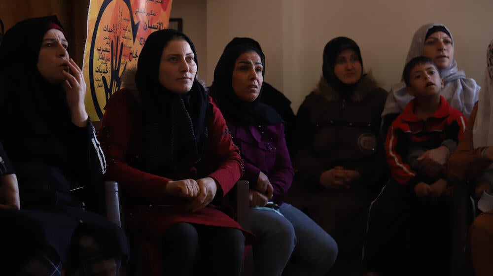 Un grupo de mujeres y un niño sentados en el interior del centro Al-Husseiniyah en la aldea de Ashrafieha, en la zona rural de Homs.