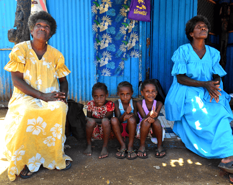 Children sit in between two women looking at the sky.